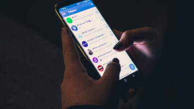 رسم توضيحي لهاتف أندرويد يفحص فيه Gemini رسالة نصية مشبوهة من رقم مجهول