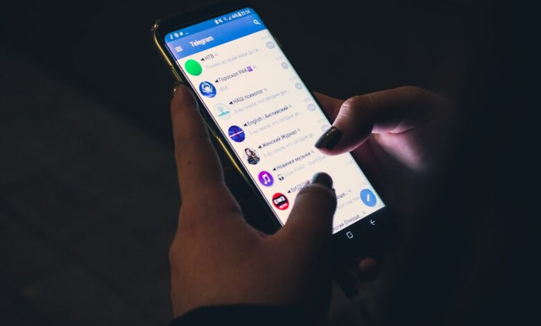 رسم توضيحي لهاتف أندرويد يفحص فيه Gemini رسالة نصية مشبوهة من رقم مجهول