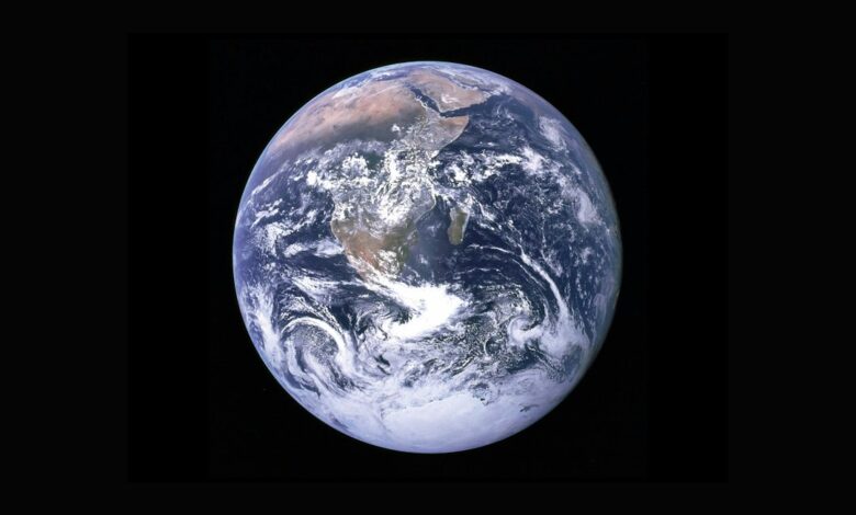 كرة أرضية بكسلية بلونين تركوازي وأرجواني فوق شعار OlmoEarth 1.3 على خلفية خضراء داكنة